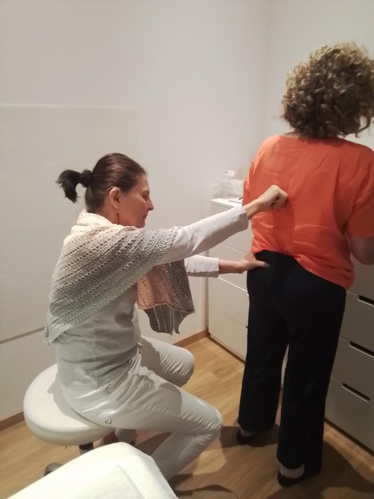 Barbara Schütz untersucht Rücken und Hüfte einer stehenden Patientin